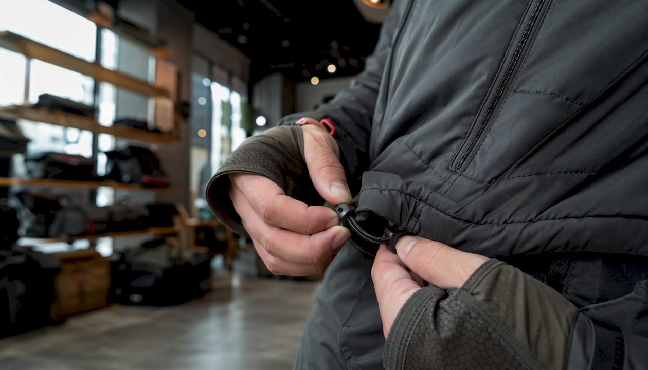 Hands adjusting insulated mid layer jacket cords