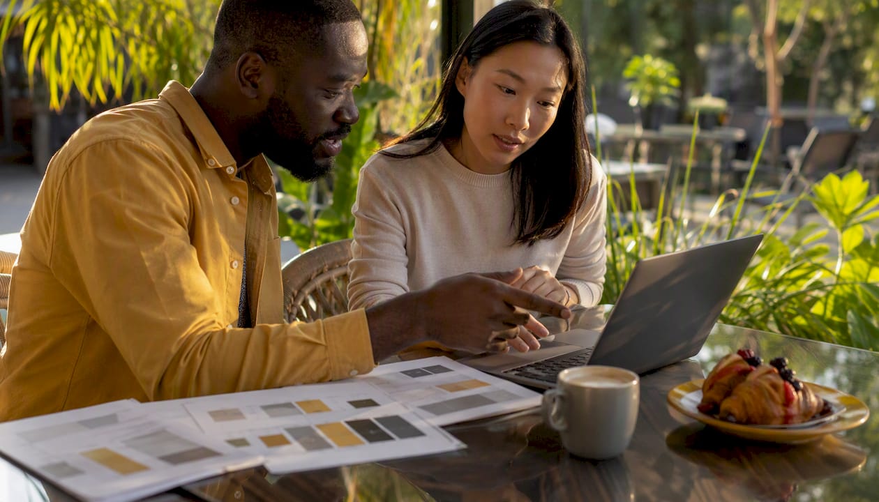 Two people collaborating on laptop and charts