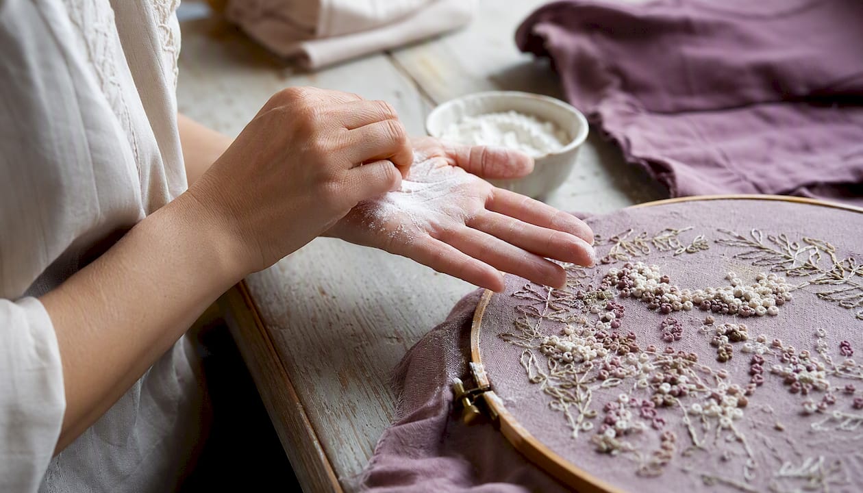 Hands dusting fingertips with cornstarch on dark fabric