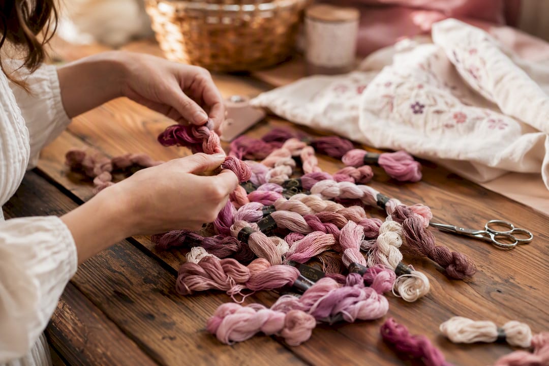 Hands photographing embroidery floss skeins with smartphone