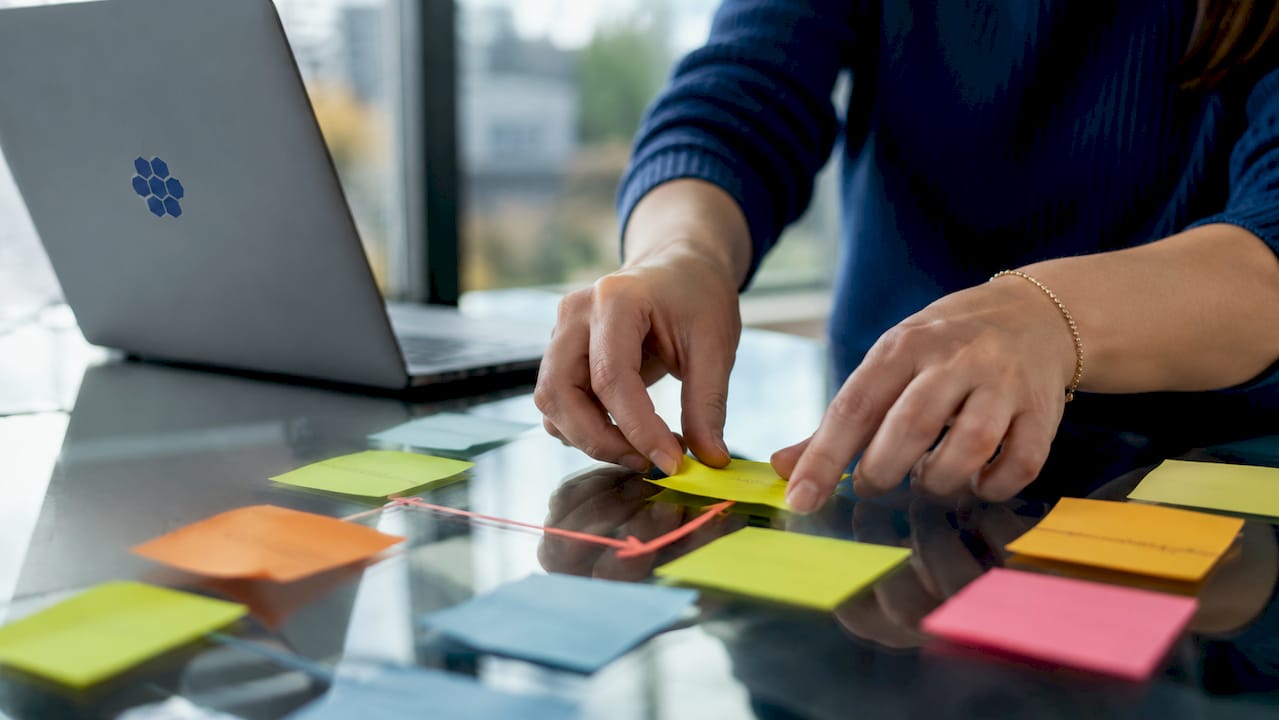 Hands arranging sticky notes showing task dependencies