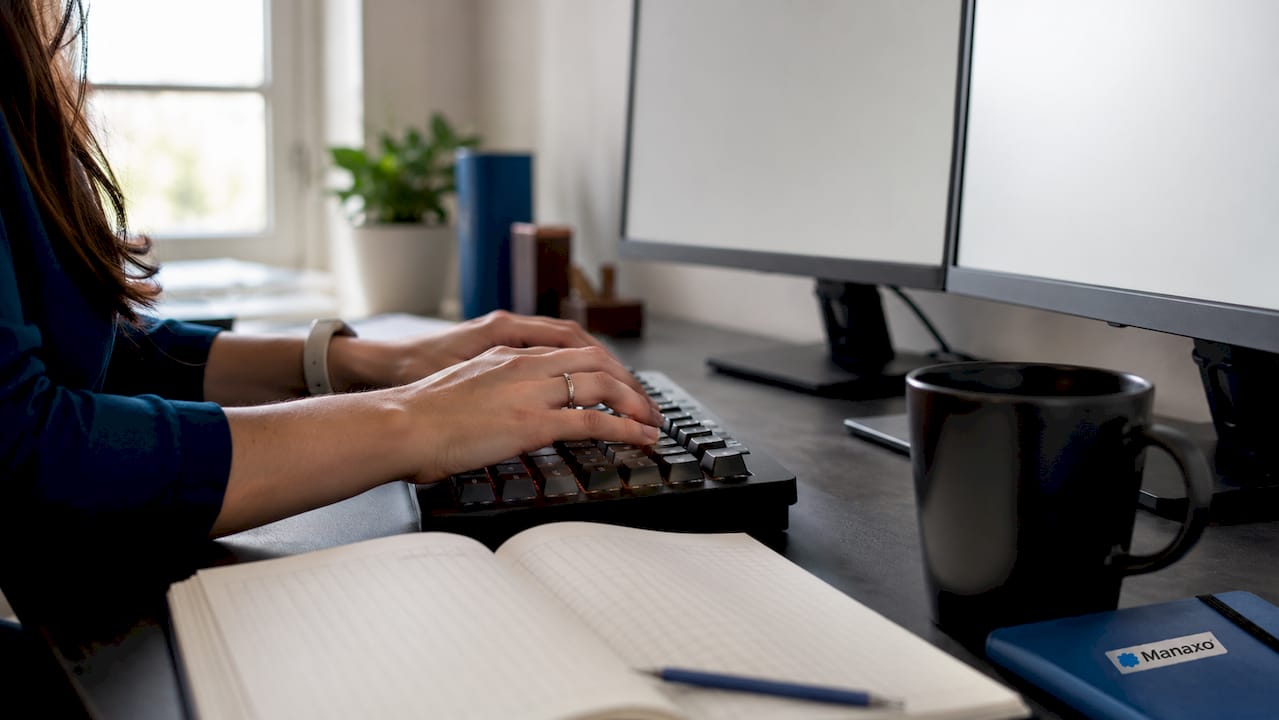 Close-up of hands typing at corporate workstation