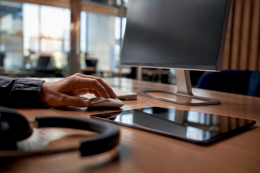 Hand adjusting mouse near monitor and tablet