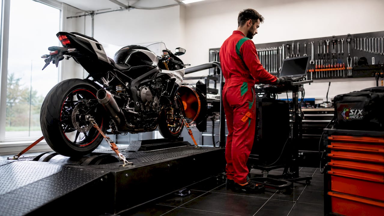 Técnico ajustando una motocicleta en una máquina de dinamómetro.