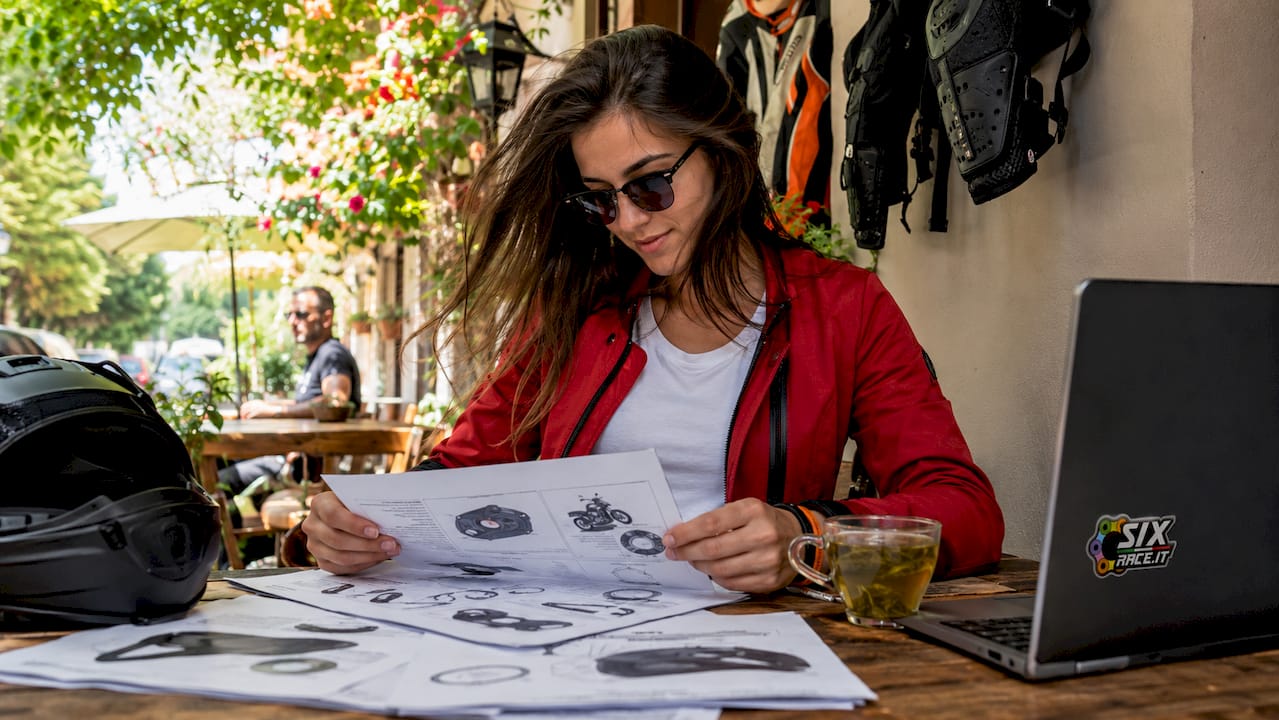 Mujer revisando la certificación de piezas de motocicleta en un escritorio