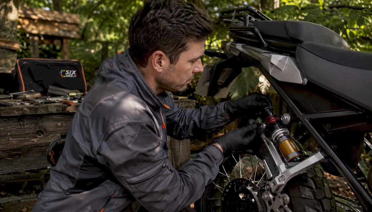 Meccanico che regola il collare di precarico posteriore della motocicletta all'aperto