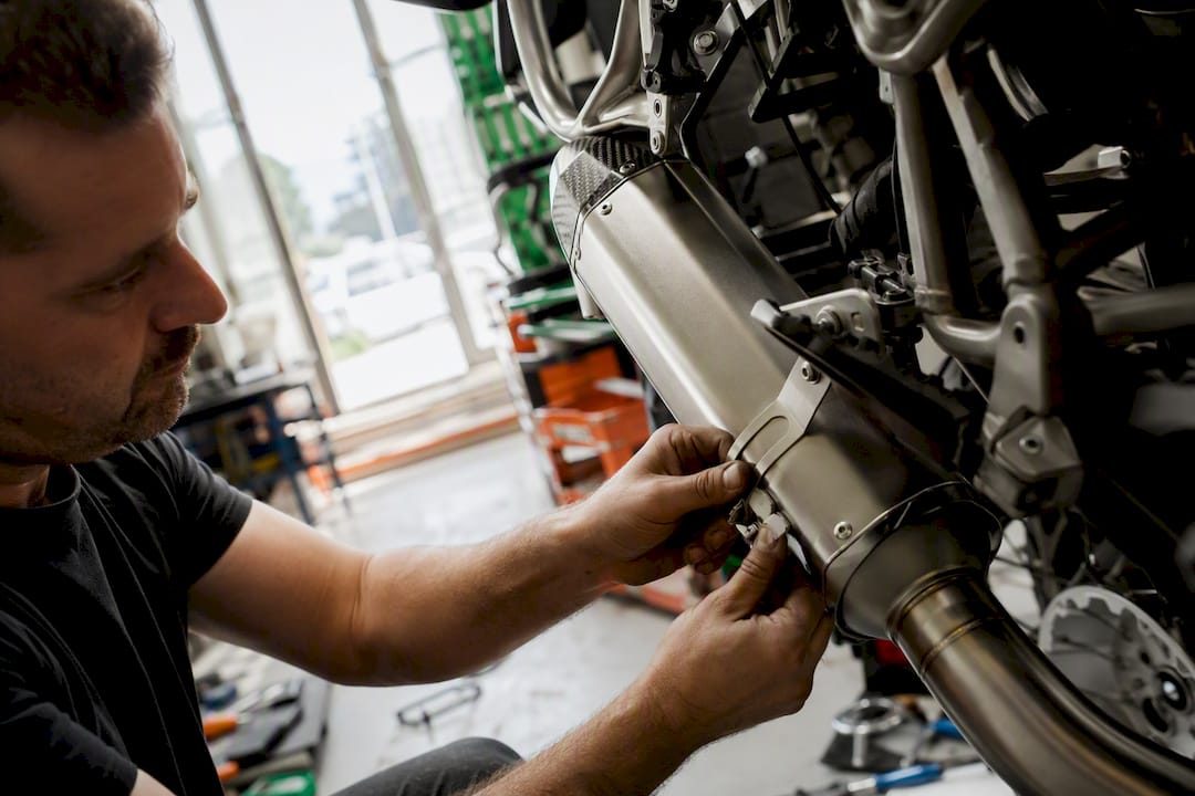 Hands fitting Euro 5 exhaust in workshop