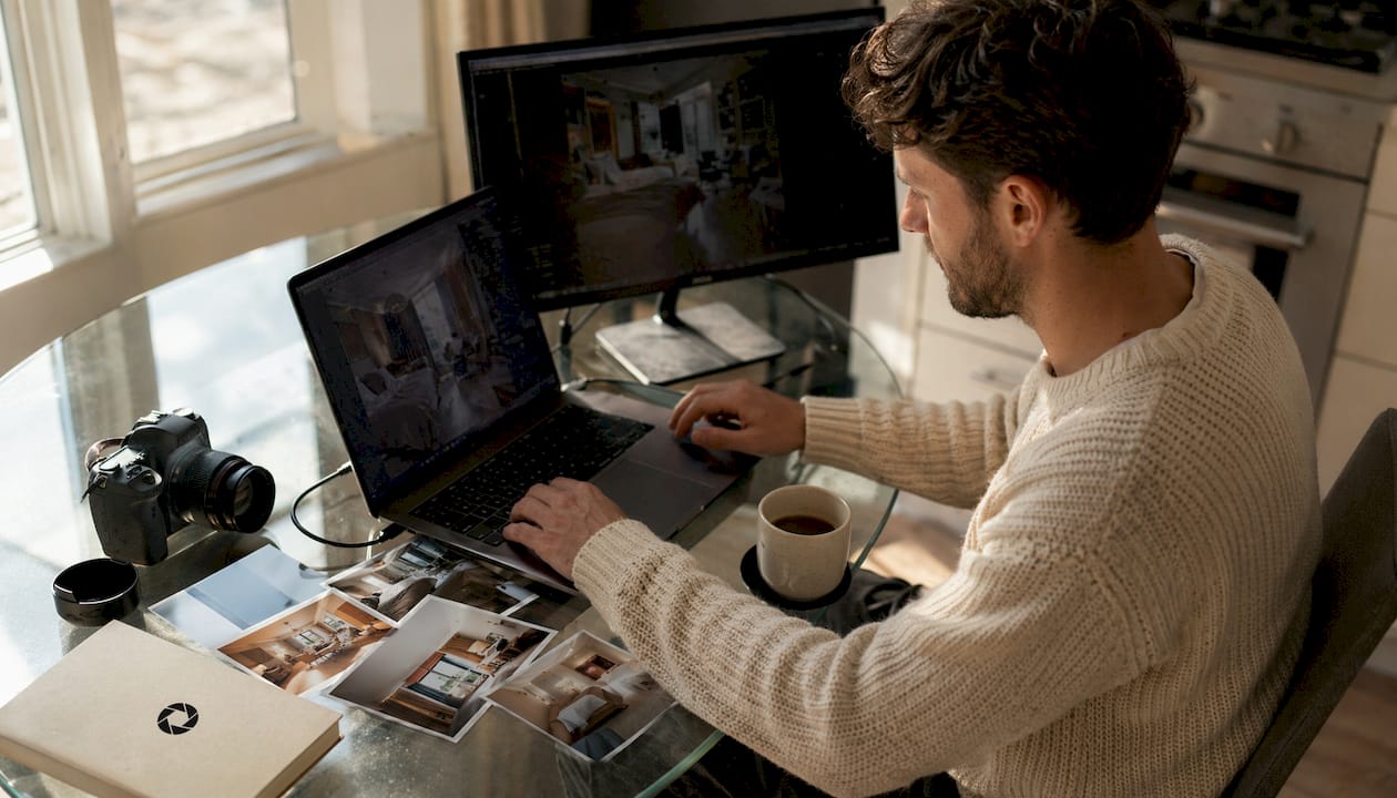 Real estate photographer editing photos on laptop and monitor