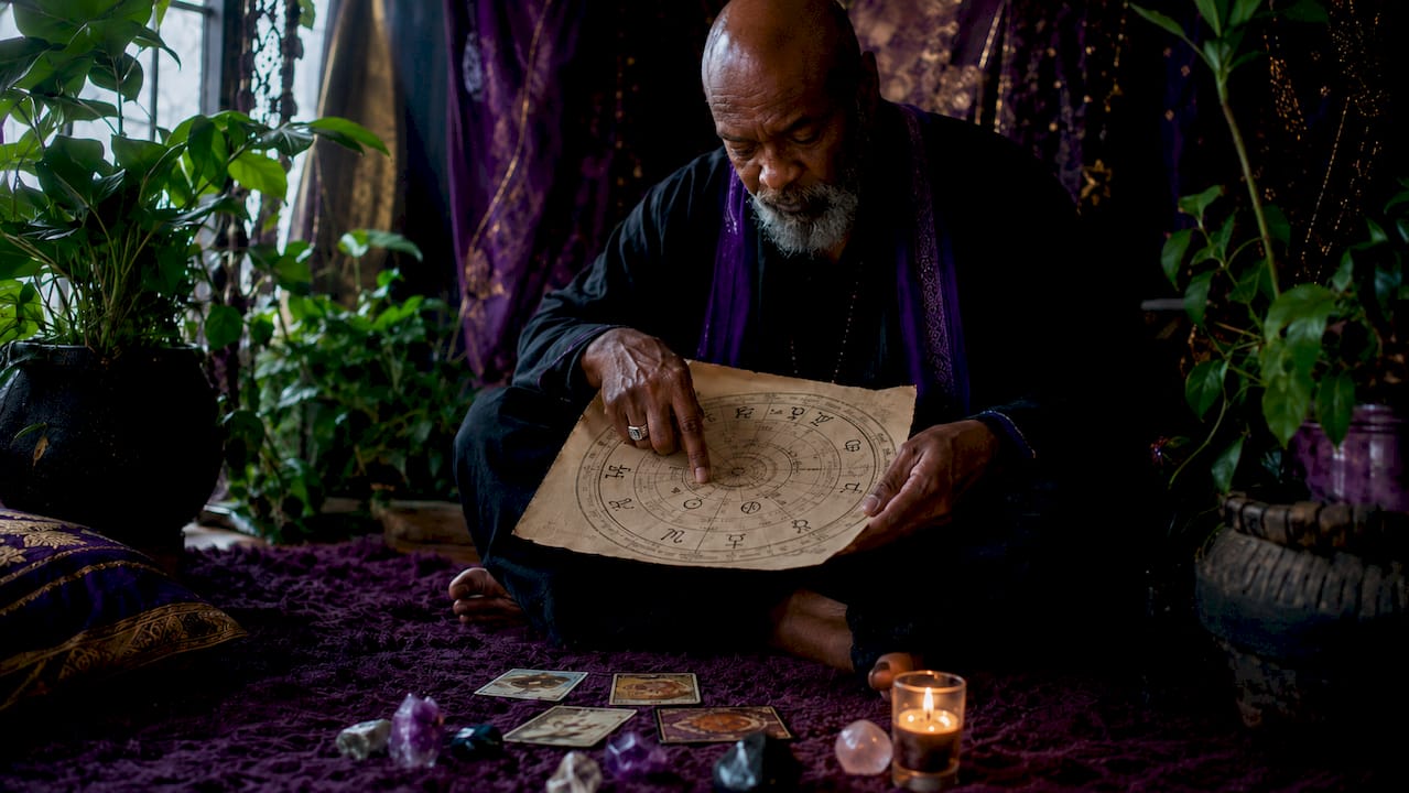 Hands tracing planetary archetype symbols on chart