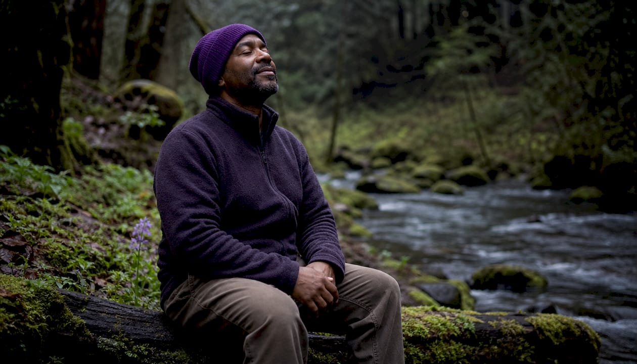 Man relaxing beside creek in nature