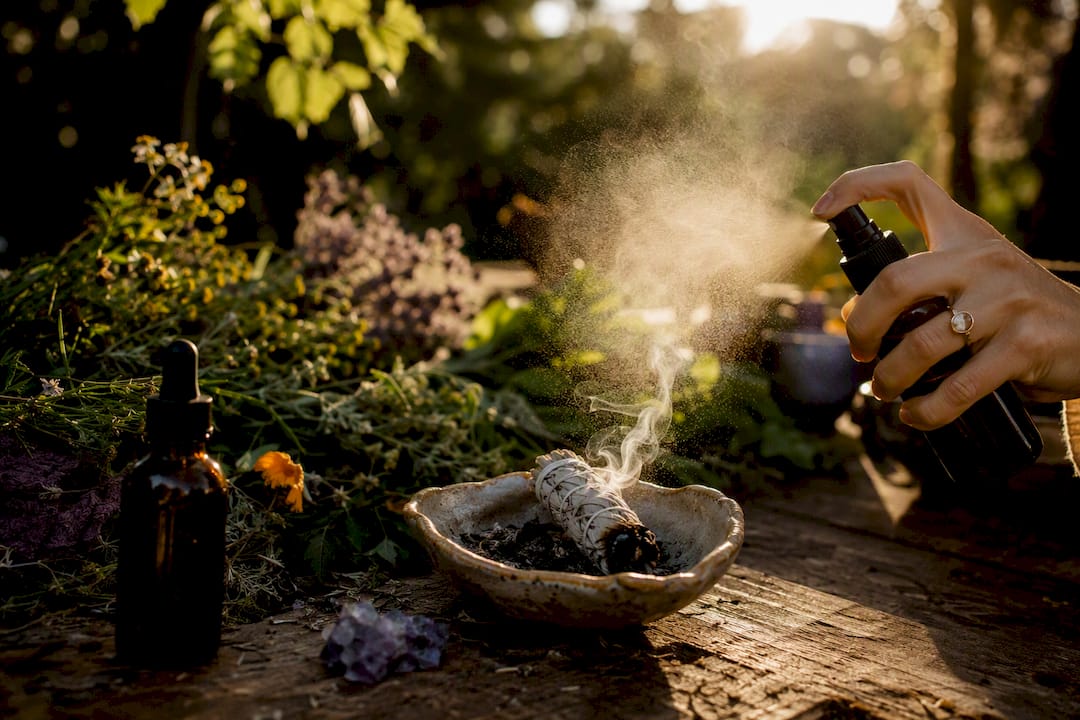 Tincture bottle, mist spray, and smudge herbs on table