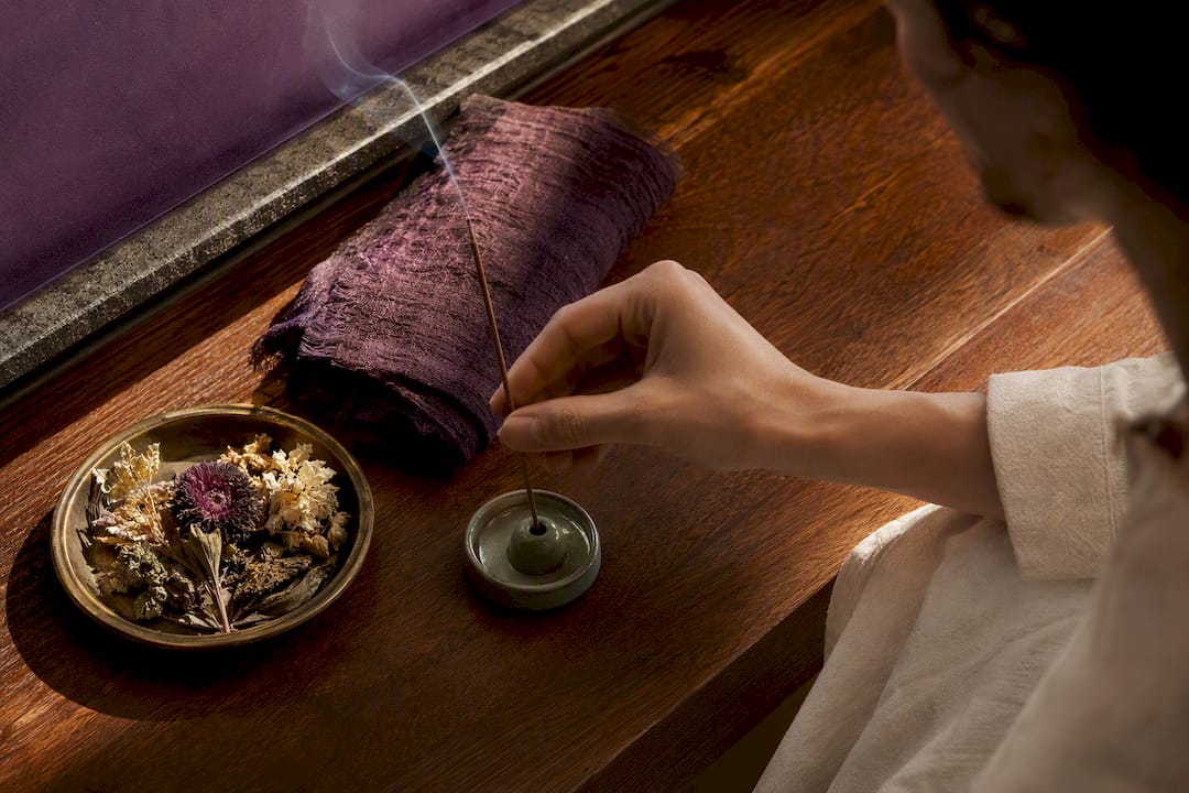 Person placing incense in a meditation nook