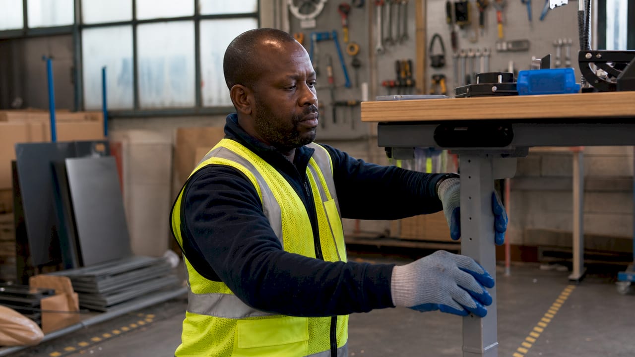 Male factory worker adjusting ergonomic workstation height