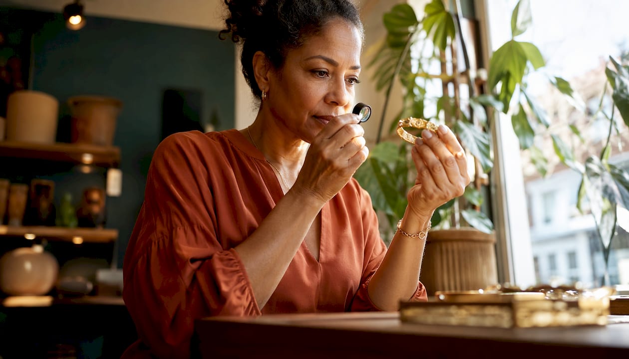 Woman inspecting gold plated necklace closely