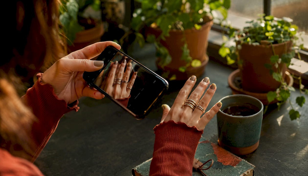 Photographer capturing photo of finger ring stack outdoors
