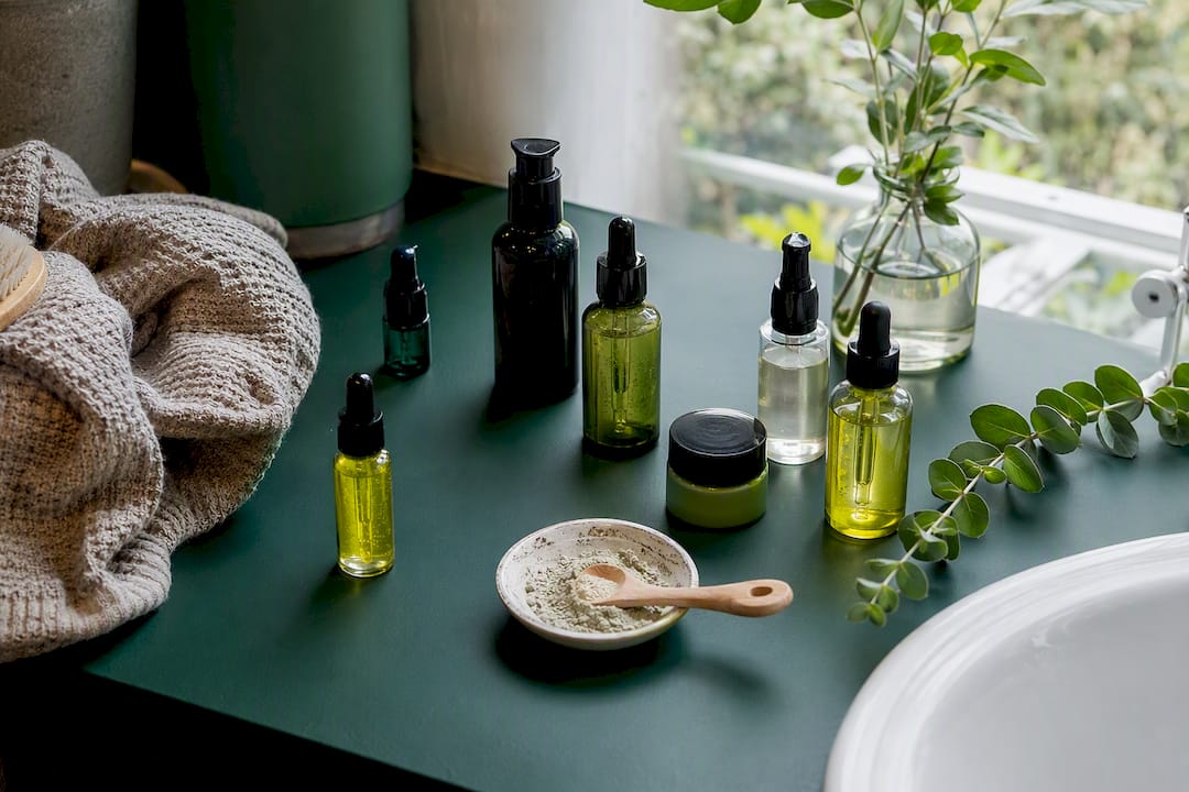 Skincare bottles and sunscreen on green vanity