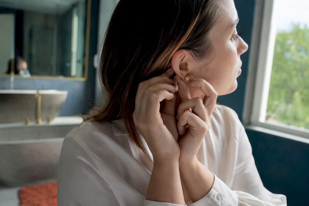 Woman adjusting gold stud earring