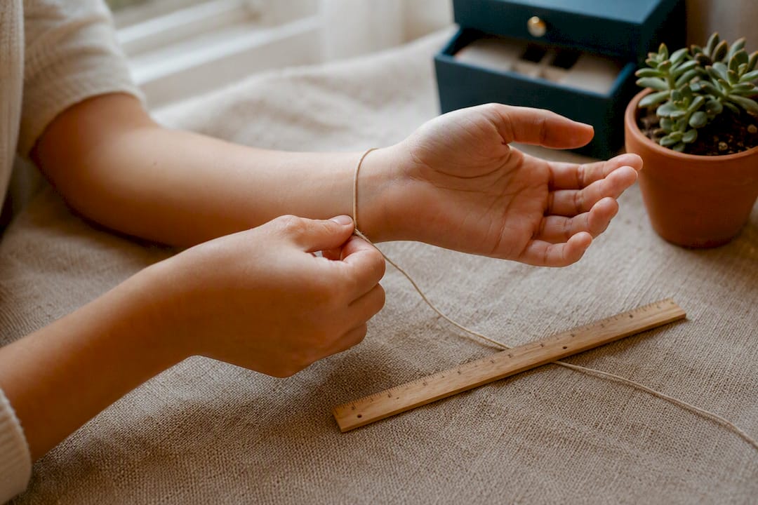 Hands measuring wrist with string and ruler