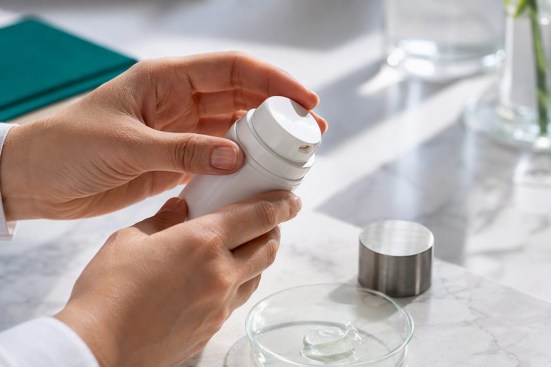 Hands examining opaque airless skincare packaging