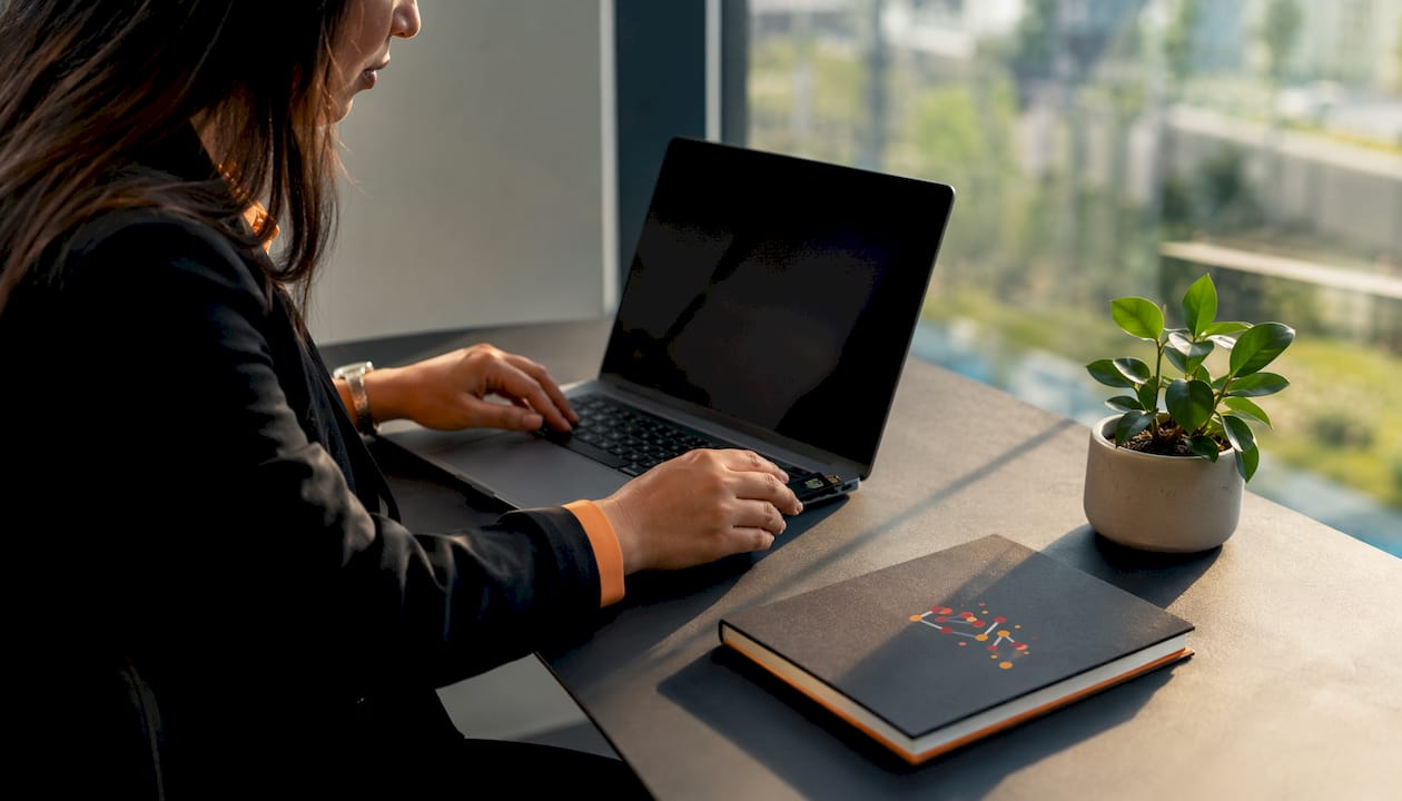 Hands holding hardware MFA token near laptop