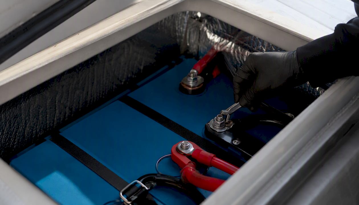 Gloved hand inspecting lithium marine battery terminals
