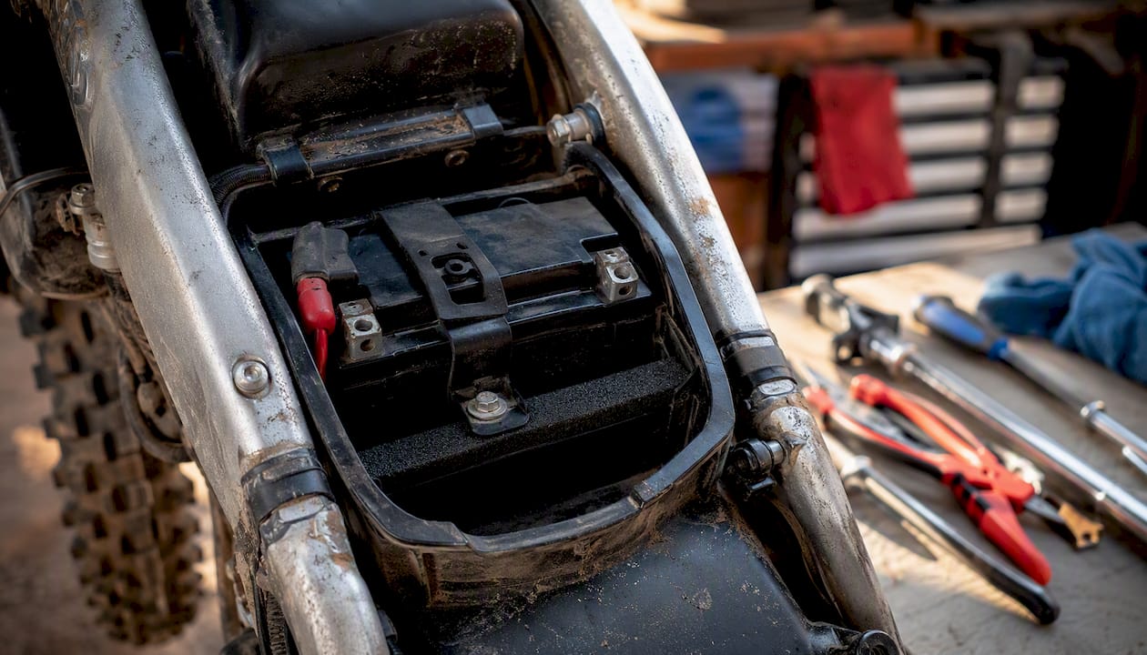 Battery secured with foam shim and strap in dirt bike battery box