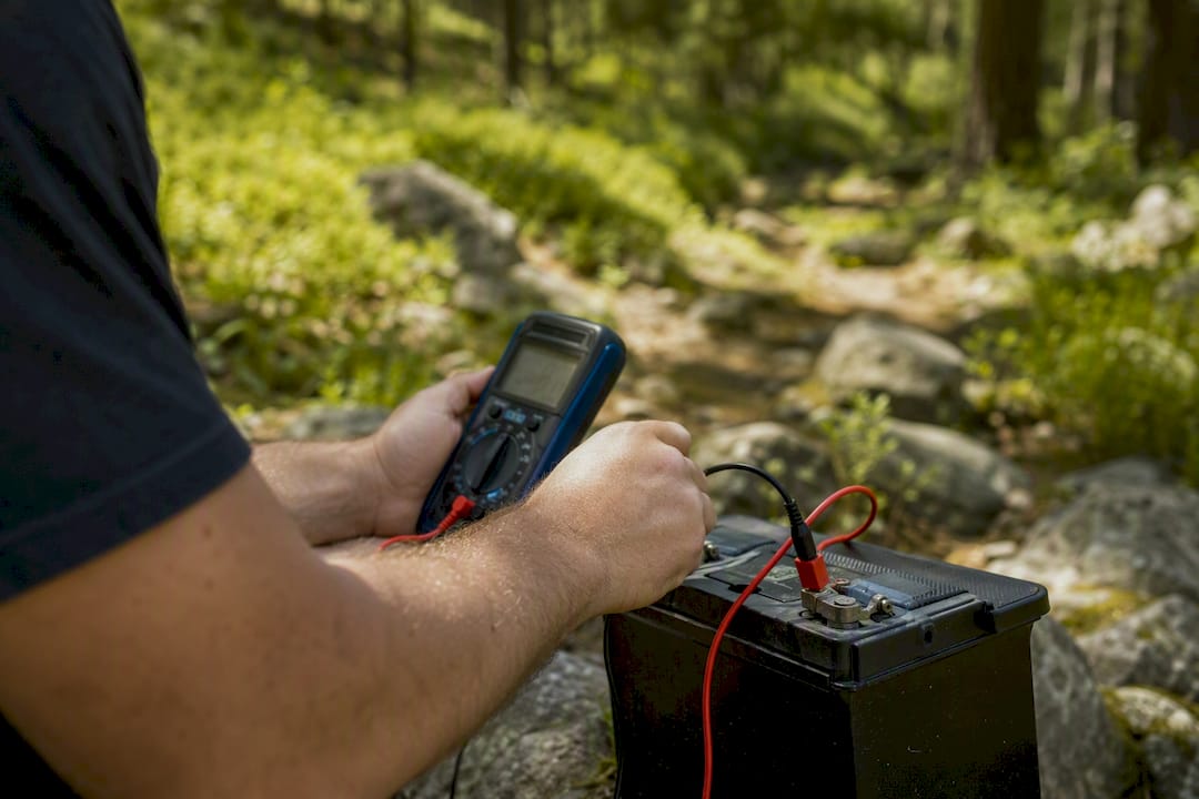 Hands testing battery voltage with multimeter