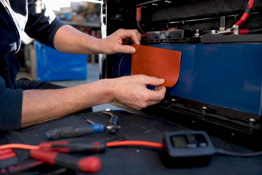 Hands fitting silicone heating pad on battery