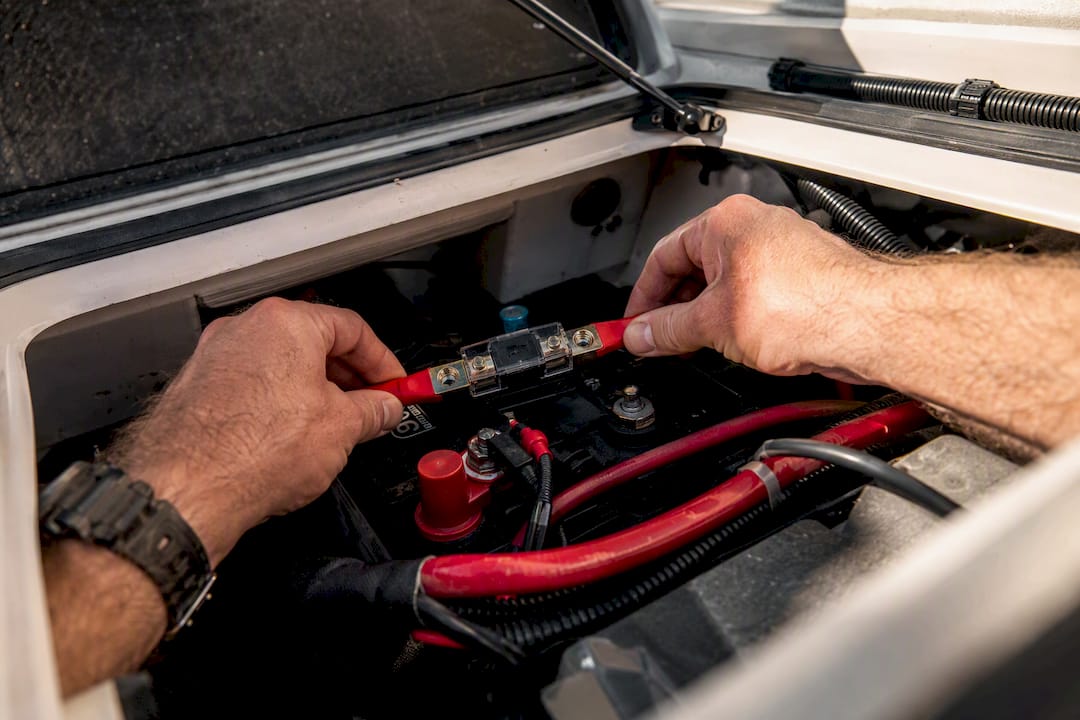 Hands installing fuse near battery terminal