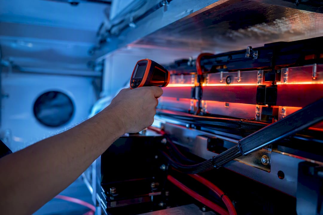 Hand measuring battery temperature with infrared tool