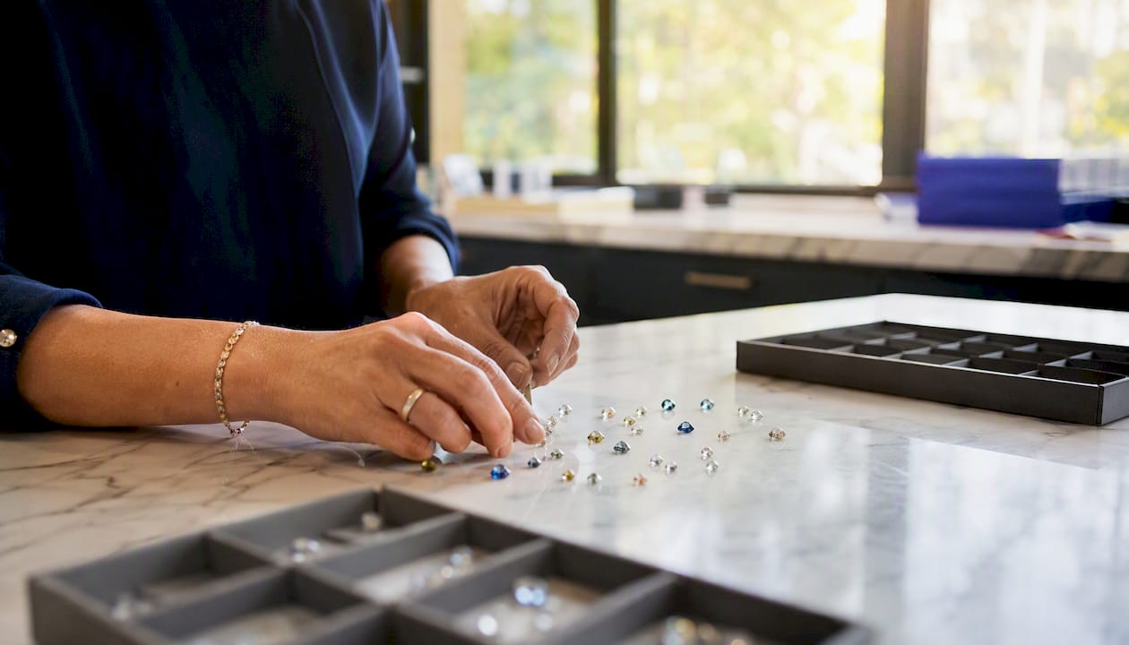 Hands documenting loose gemstones at inventory station