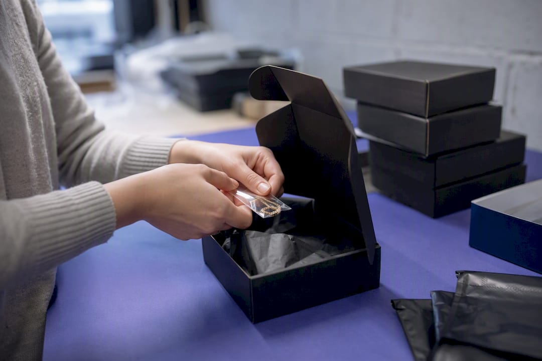 Hands packing jewelry components for shipment