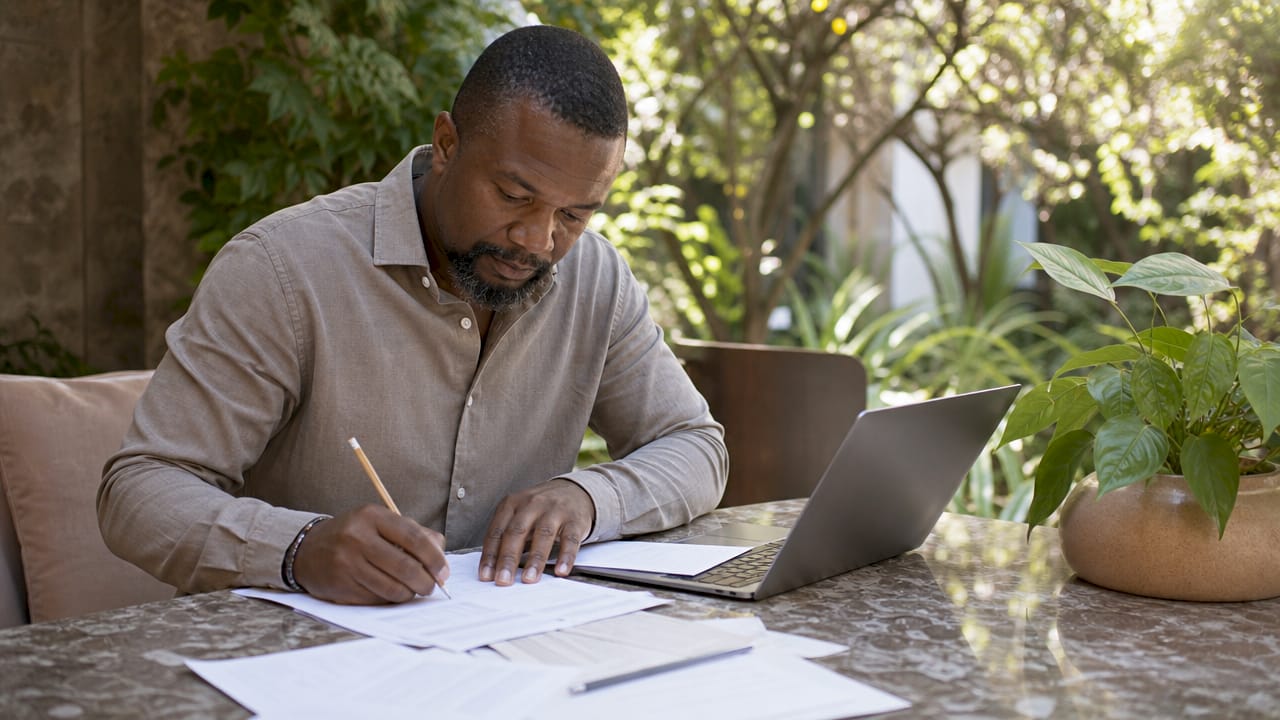 Hands filling tax estimate worksheet on desk