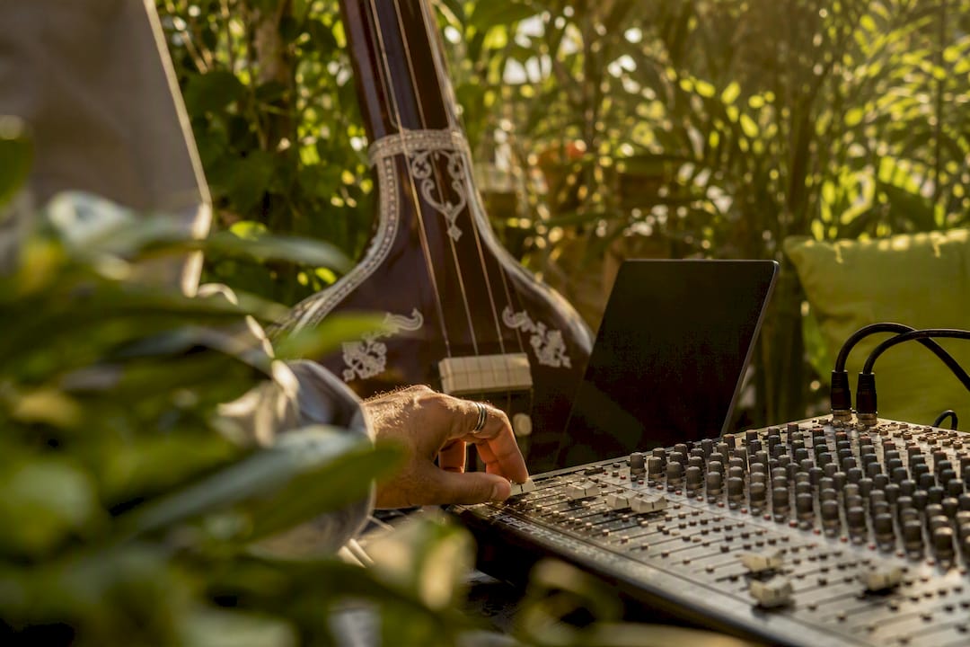 Hands adjusting audio mixing console near tanpura
