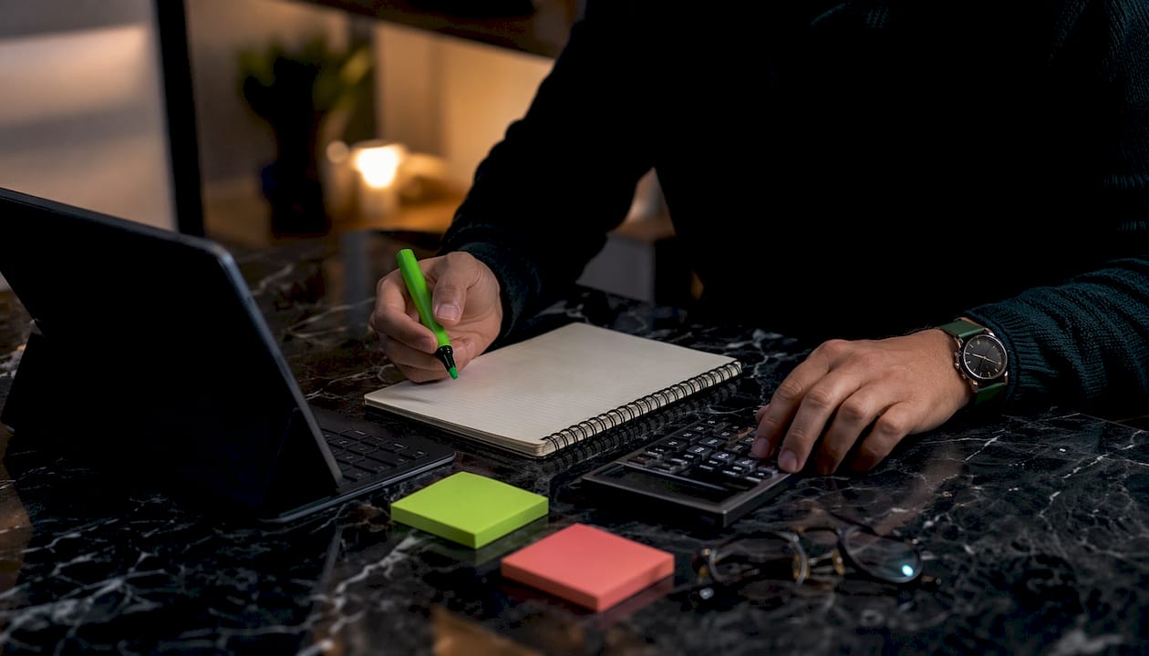 Trader's hands noting systematic trade logs on desk.
