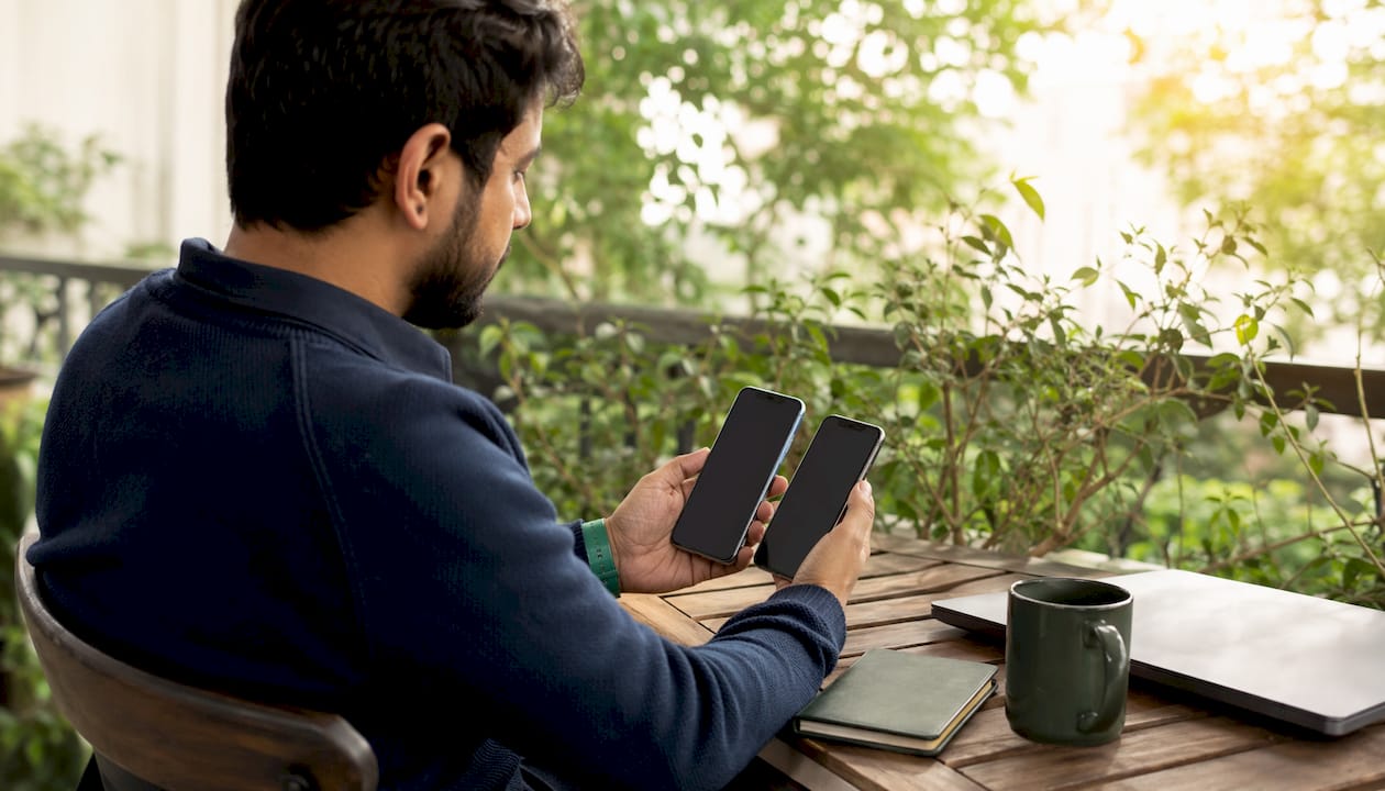 Investor comparing investment apps on smartphones at home
