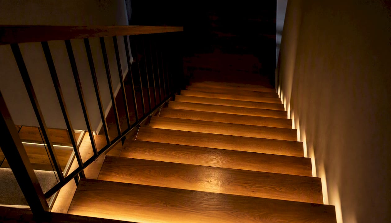 Scară interioară cu trepte luminate cu LED-uri, pentru un ambient modern și sigur în locuință.