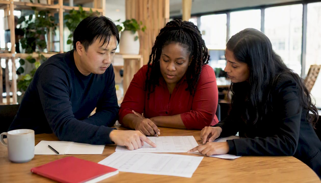 Multicultural team reviewing timesheet errors together