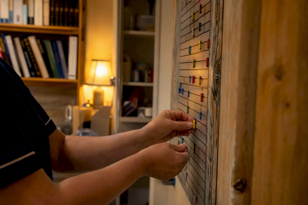 Hands arranging shift key tags on rota board