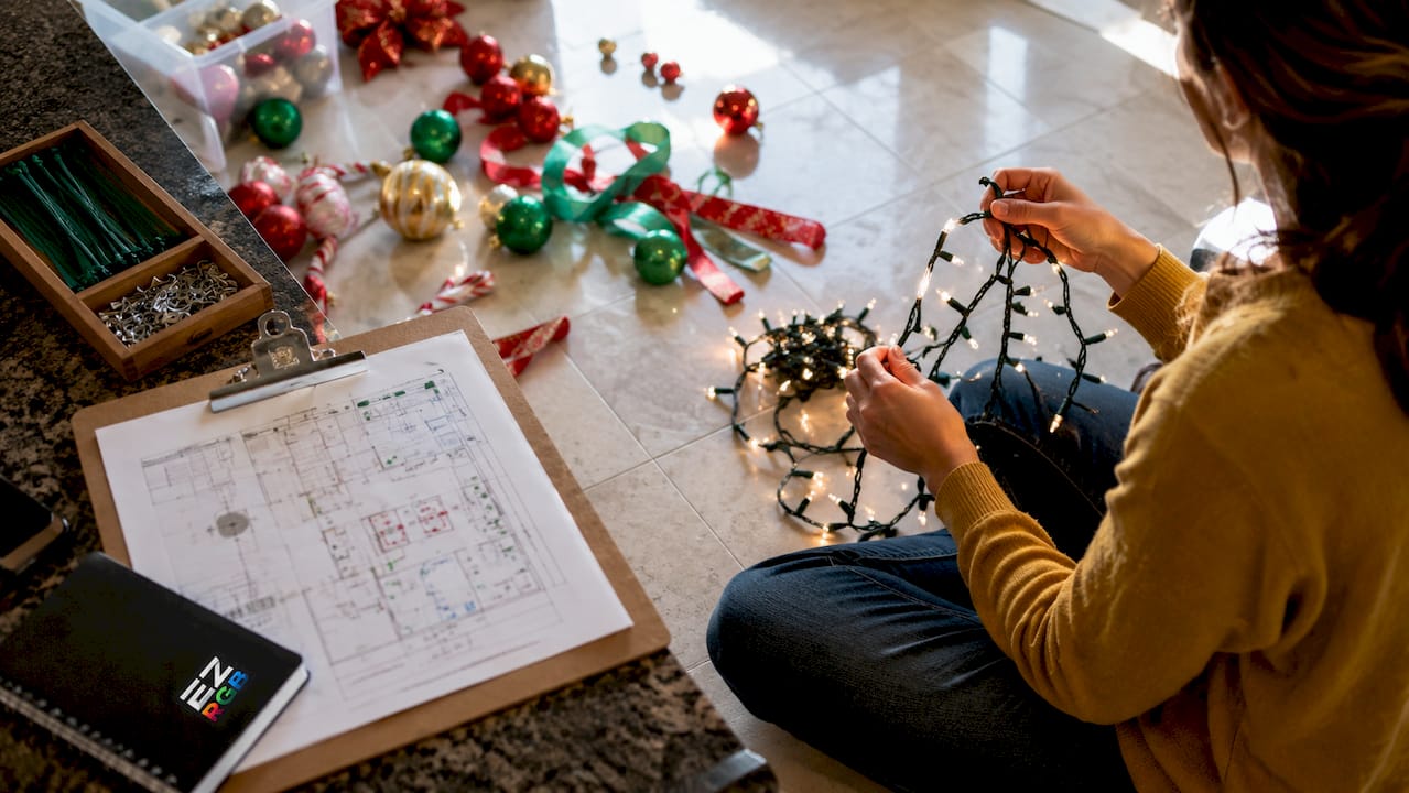Hands arranging holiday lights and planning layout