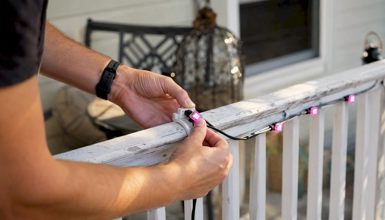 Hands clipping pixel lights to roofline with clips