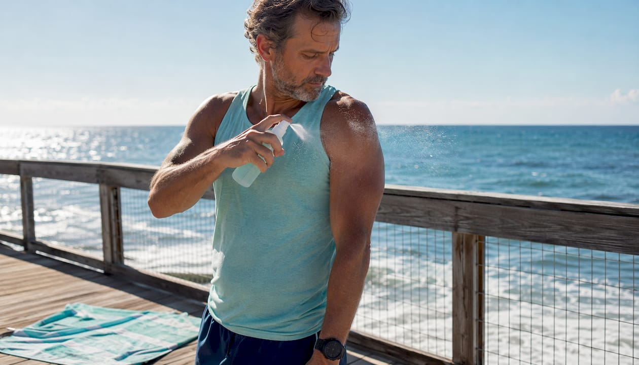 Man spraying sunscreen during outdoor jog