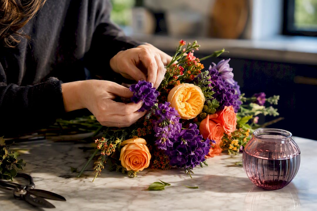 Florist hands arranging colorful flower bouquet
