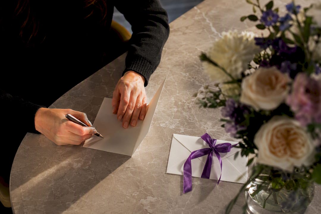 Hands writing a sympathy flower card
