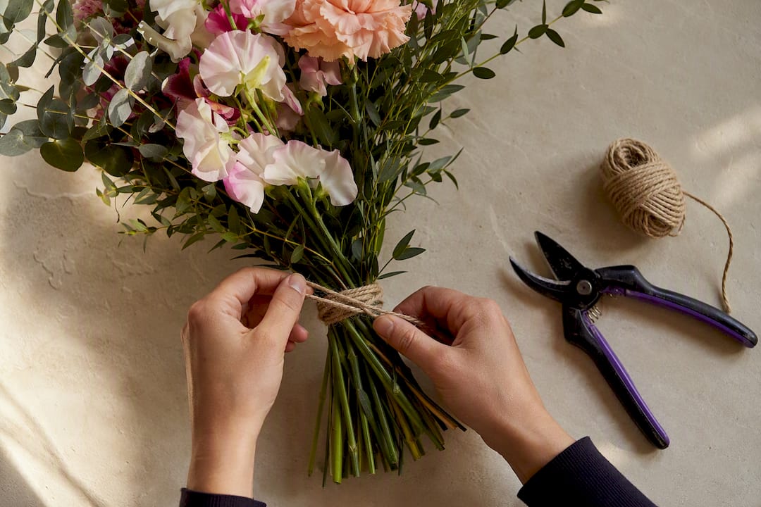 Hands tying a mixed DIY flower bouquet