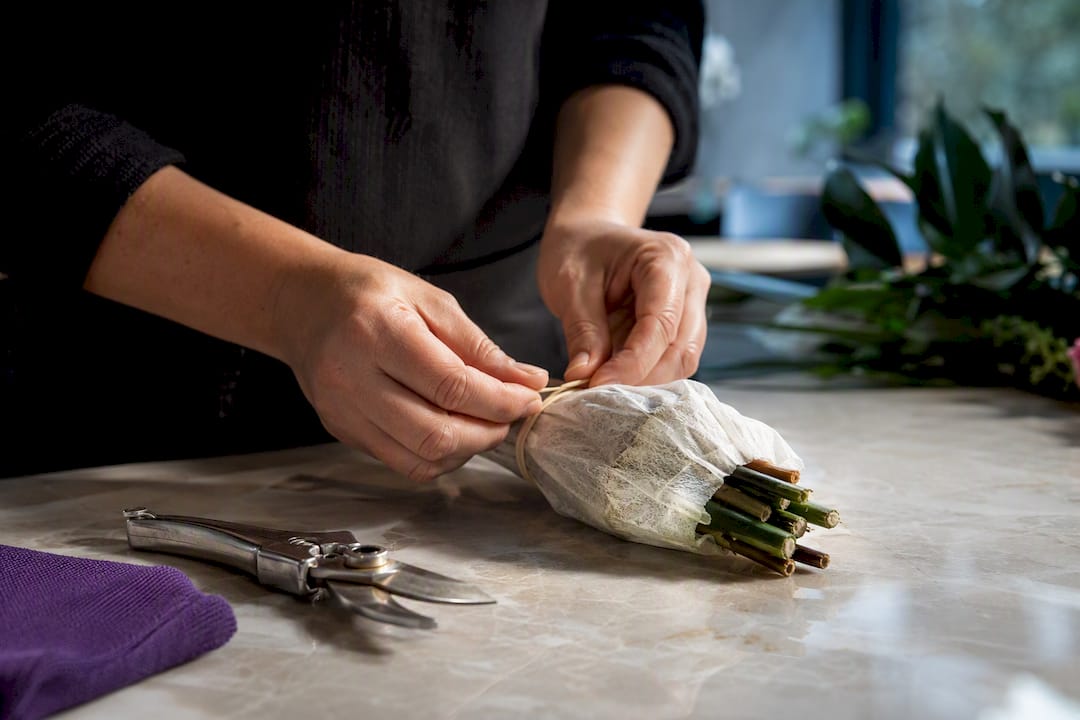 Hands sealing hydration wrap around flower stems