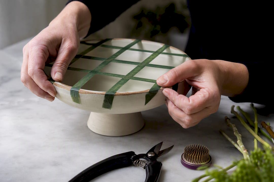 Hands creating a floral tape grid
