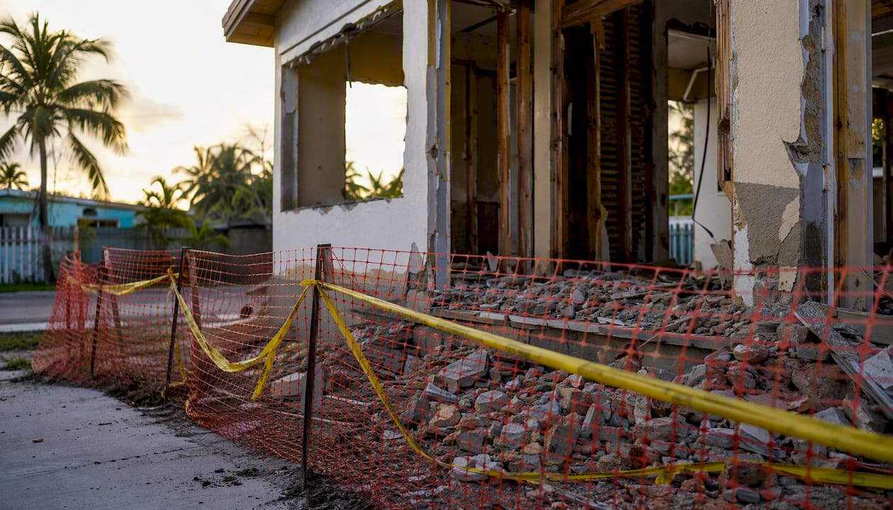 House demolition site with warning tape and rubble