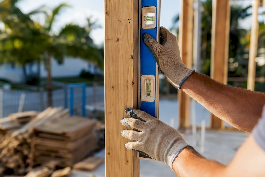 Gloved hands measuring wood beam on site