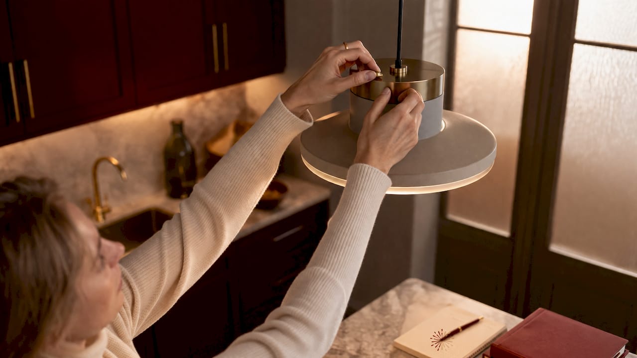 Hands adjusting warm LED lamp dimmer in cozy study